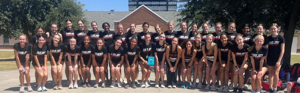 A group of people in matching black uniforms, standing in rows in front of a building.