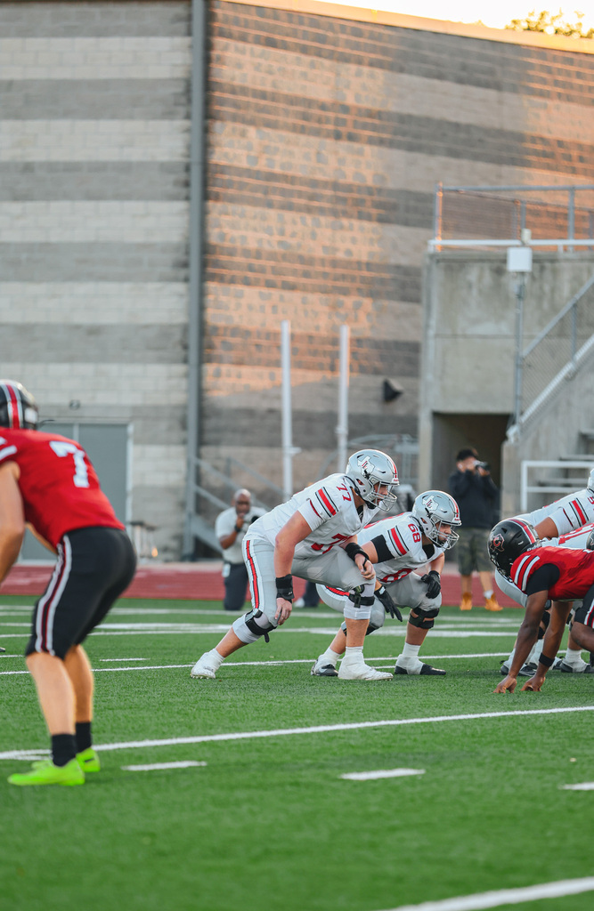 Football players on a field with white lines. Two teams face each other. Players in white uniforms are ready for the game.