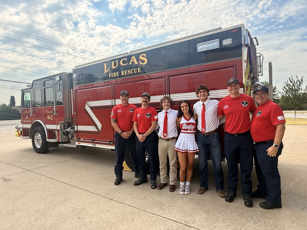 A group of people in red uniforms stands in front of a fire truck labeled "Lucas Fire Rescue."
