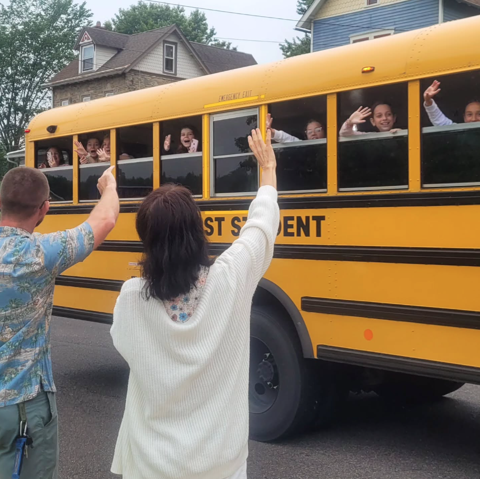 Teachers saying goodbye to students in a school bus