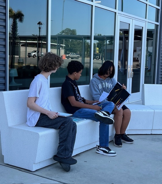 Student practicing reading aloud to other students.