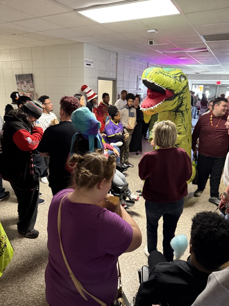 Students dancing with someone in a dinosaur costume
