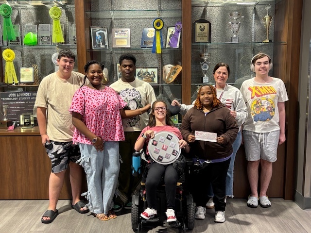 Students displaying the magnets and the donation check to LAMP