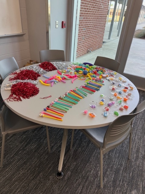 Table of items for purchase including pom poms, pencils and toys