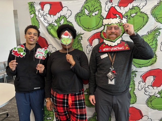 Students and an administrator in front of a grinch background