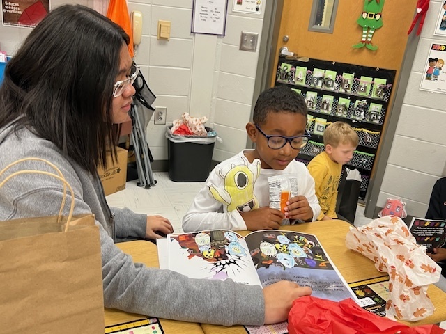 High school student reading book with elementary student