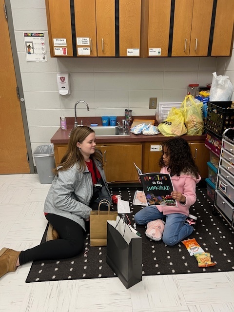 High school student reading book with elementary student