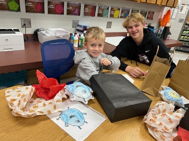 High school student gifting elementary student a book and plushie