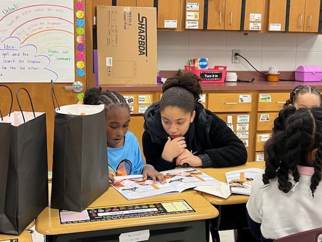 High school student reading book with elementary student