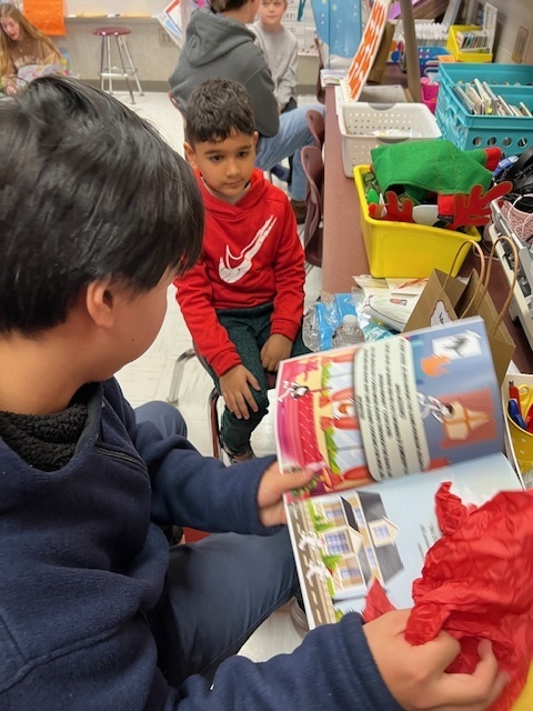 High school student reading book with elementary student
