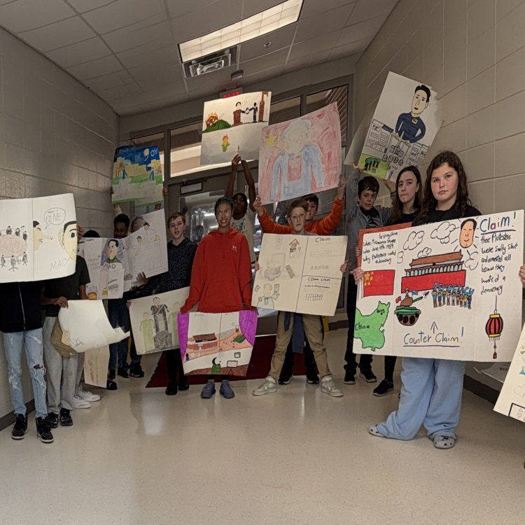 students posing with political cartoon posters