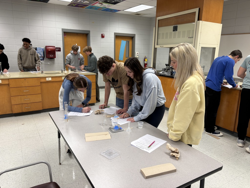 Students conducting the experiment and notating data at several lab stations