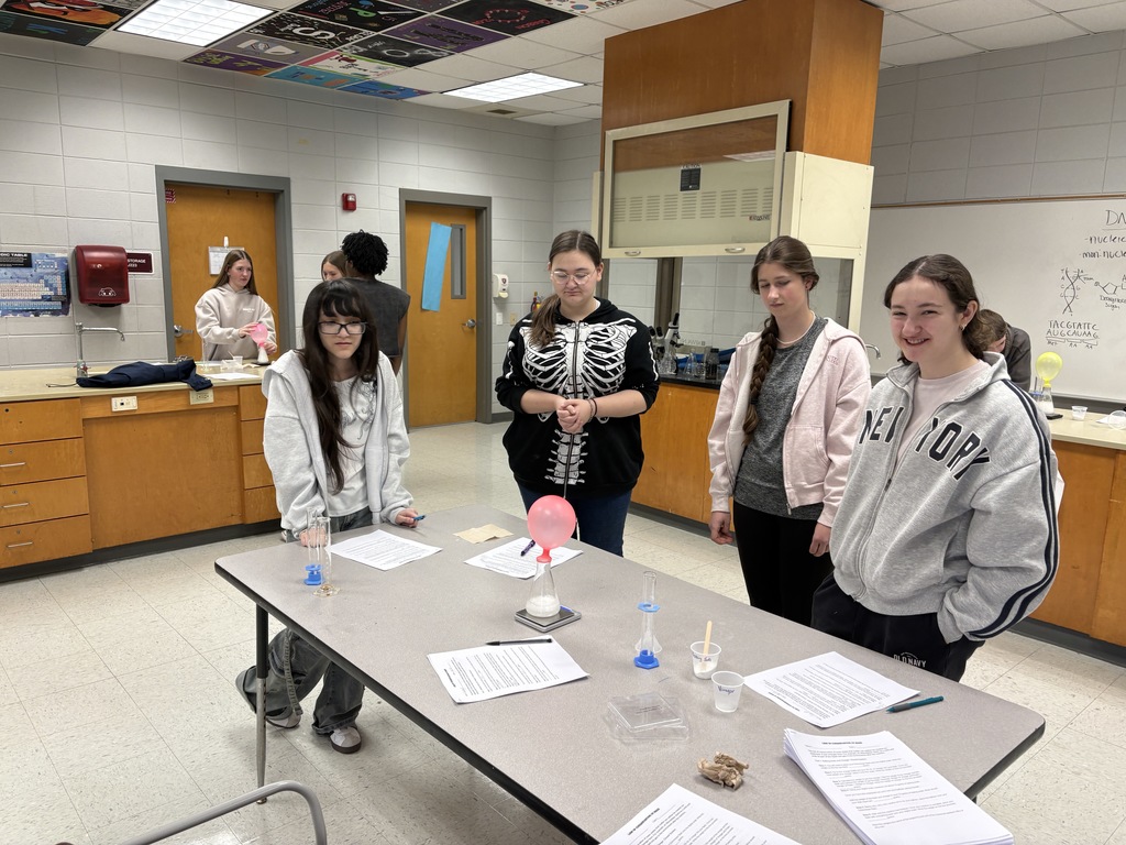 Students observing the gases being emitted blowing up the balloon on top of the beaker.