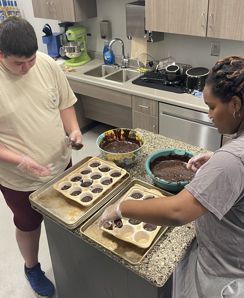 Students putting brownie batter in muffin tins