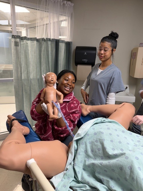 Allied health student simulating delivering a baby