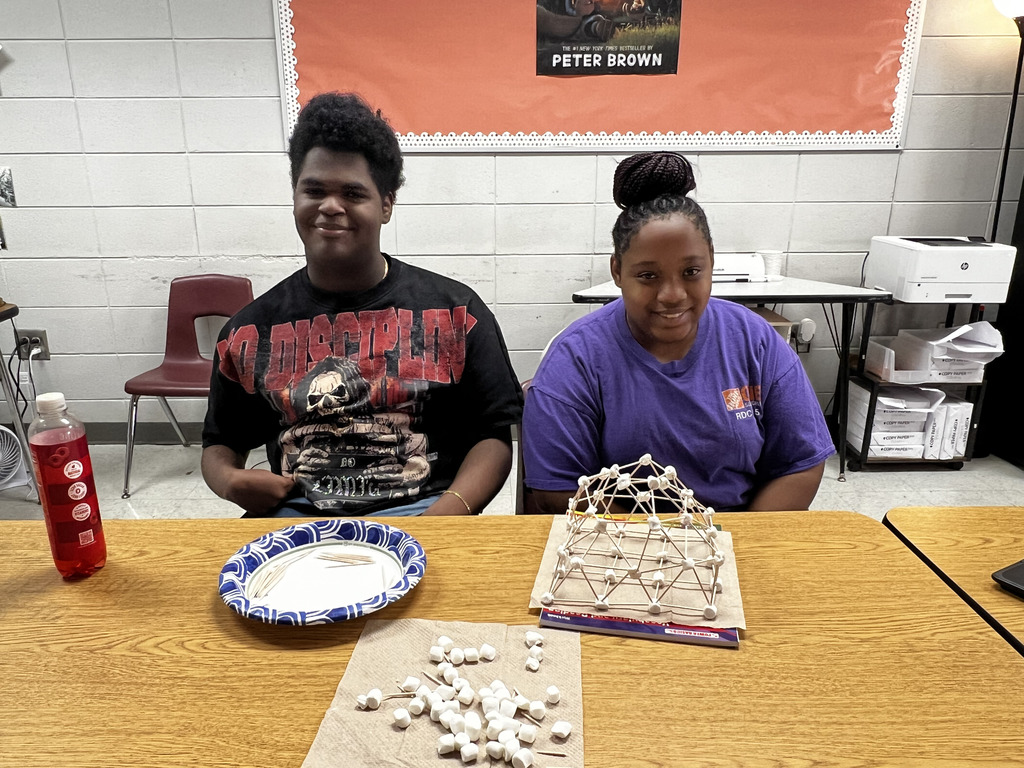Students with a structure they built out of toothpicks and marshmallows