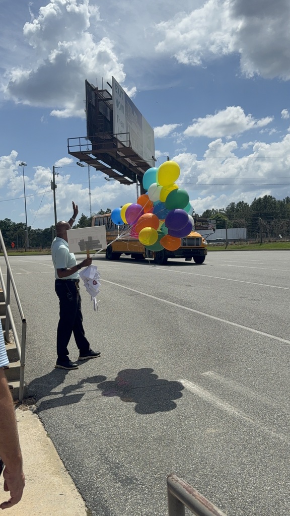 Mr. Walker waving the final bus off campus