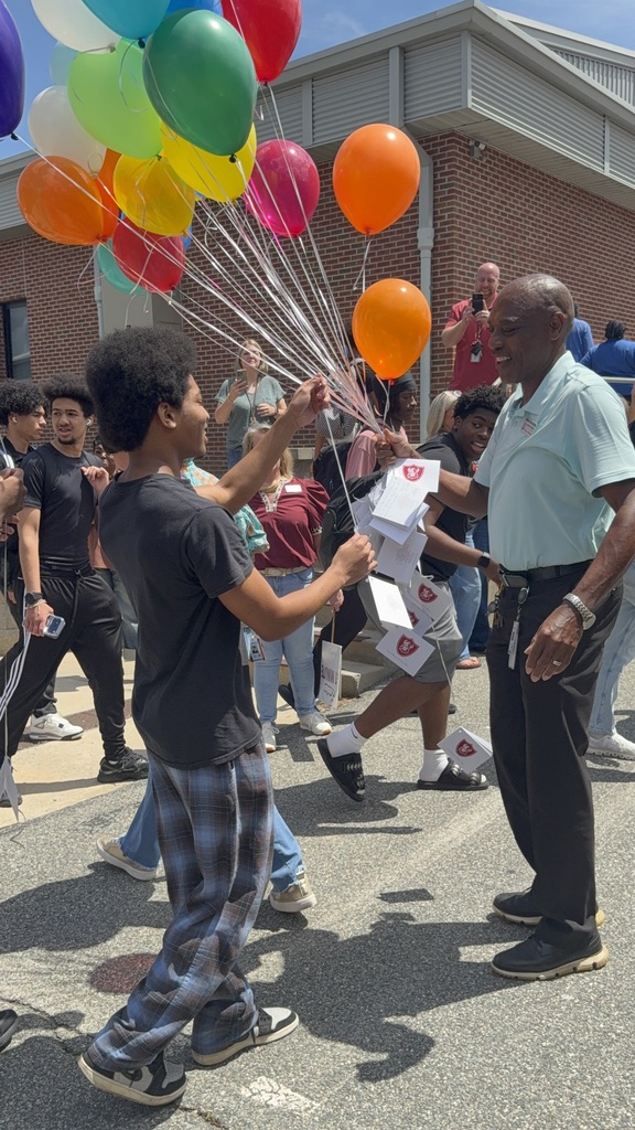 A student handing Mr. Walker a balloon