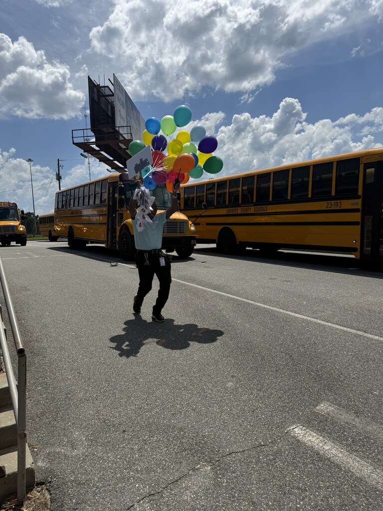 Mr. Walker with his balloons jumping for joy at his last bus duty