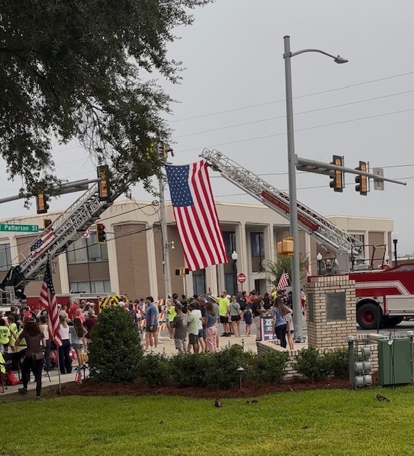 Fire trucks raising an American flag