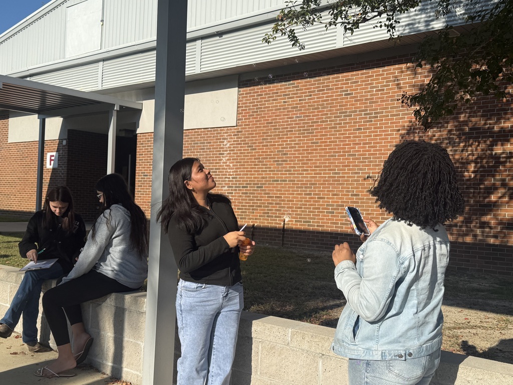 Student watching her bubble float into a tree