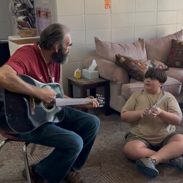 Mr. Dixon playing guitar with a student