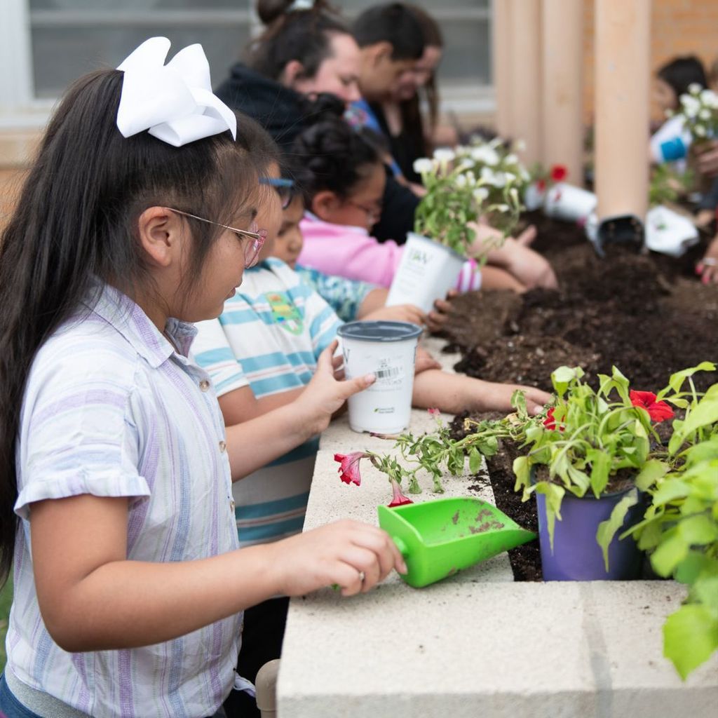 student planting with green trowel