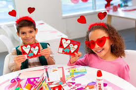 2 kids dressed for Valentines holding Valentine cards