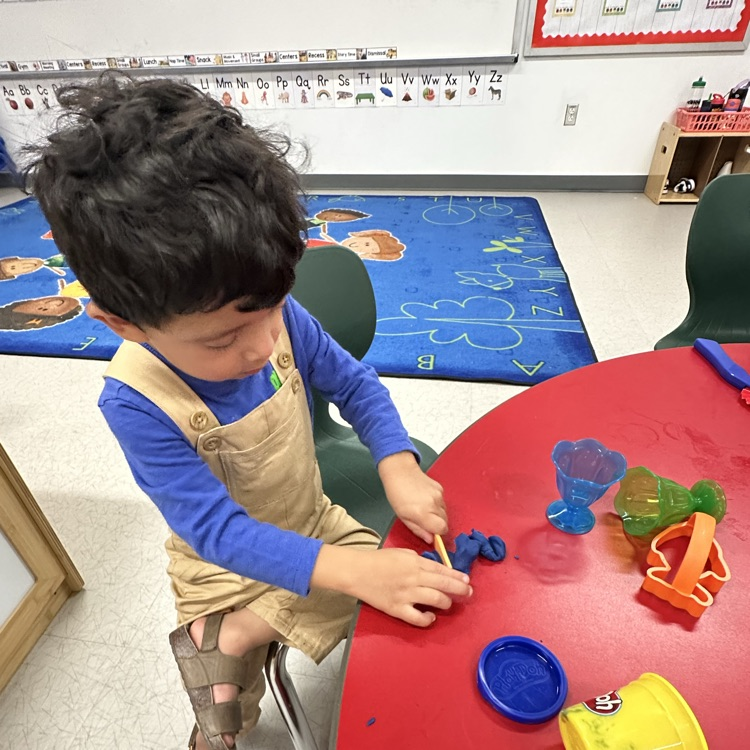 student holding plastic knife cutting playdough