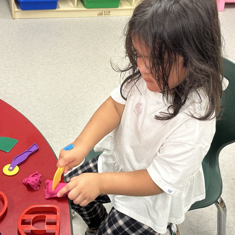 student cutting playdough with a plastic knife