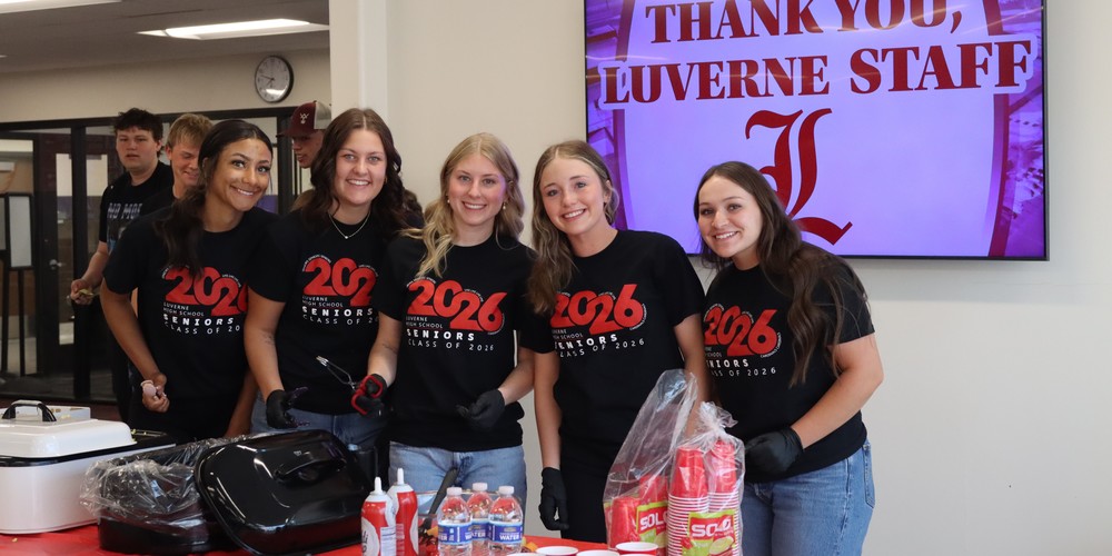 students pose for a picture as they serve breakfast to the staff