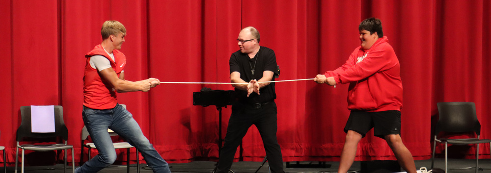 two students play tug of war while the magician stands between them