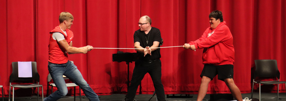 two students play tug of war while the magician stands between them