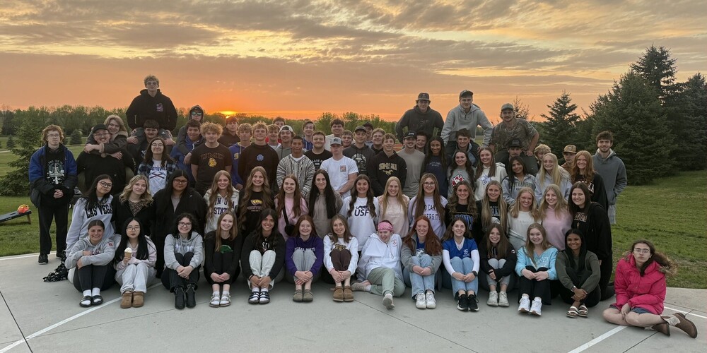 Senior class poses with the sun setting in the background at the end of their senior year.