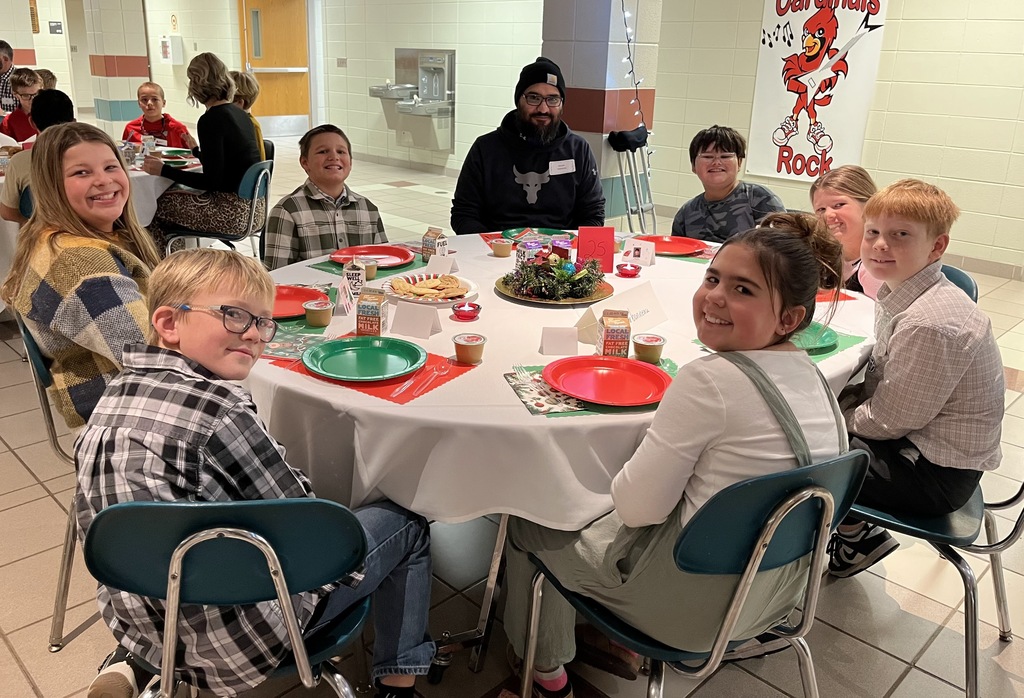 Students and parents eating Respect lunch at round tables.