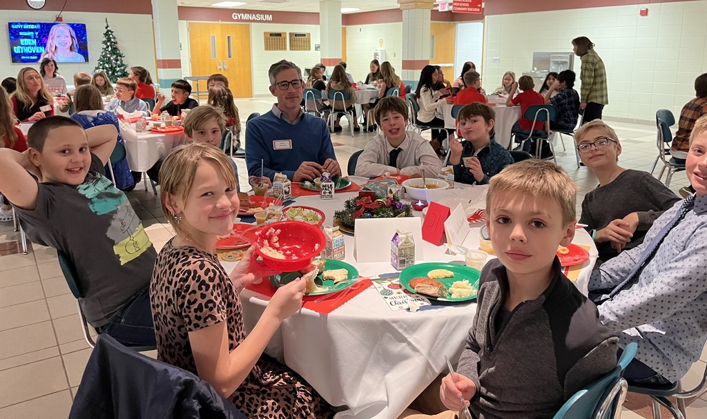 Students and parents eating Respect lunch at round tables.