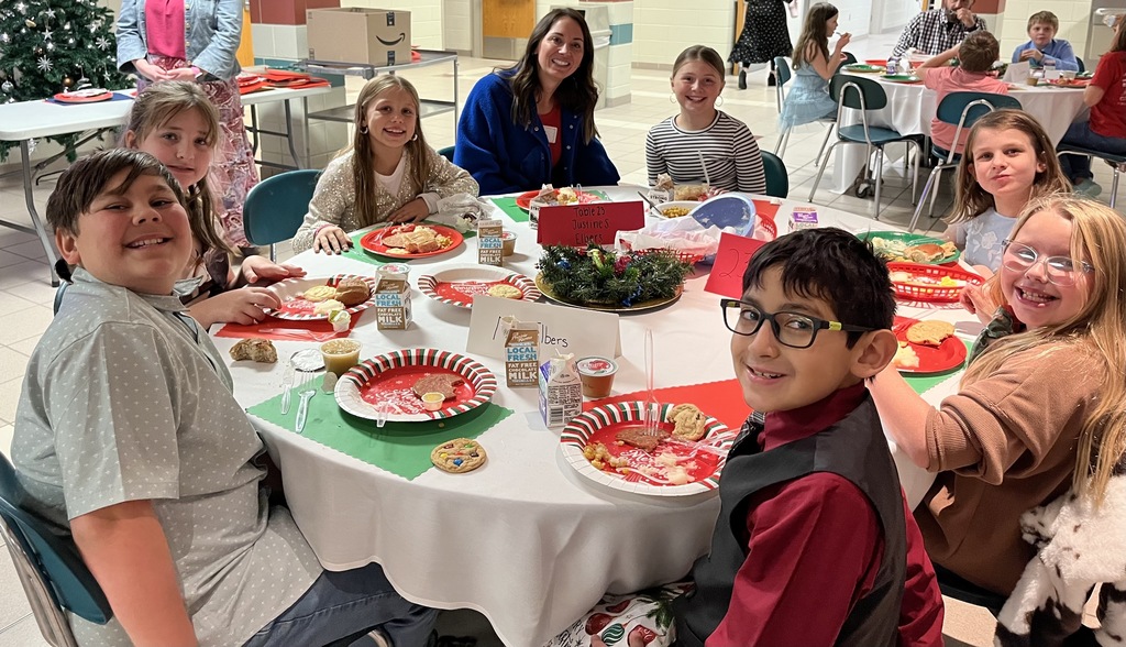 Students and parents eating Respect lunch at round tables.