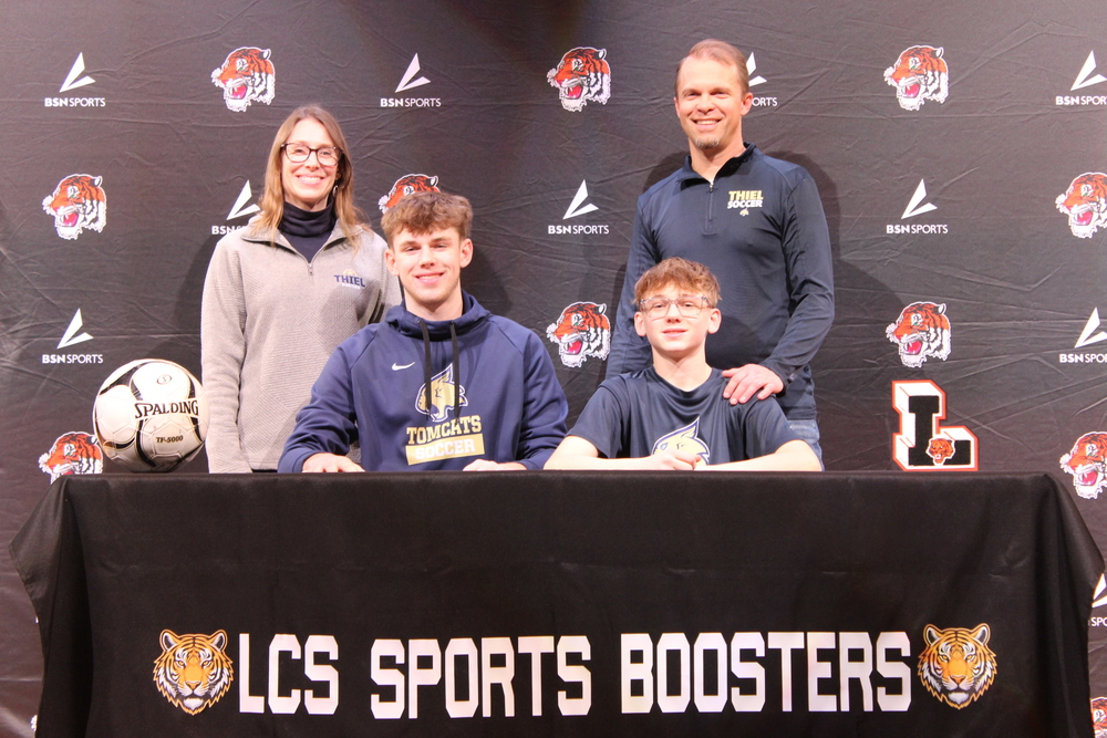 two adults standing behind their two children seated at table