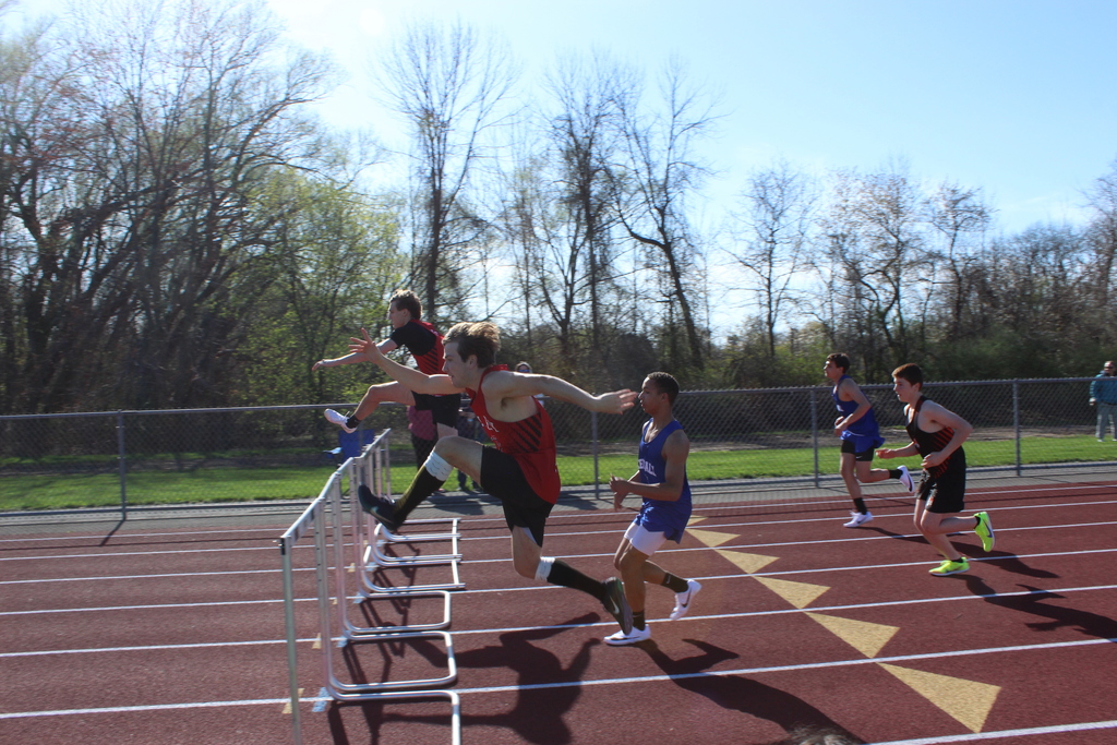 boys jumping over hurdles