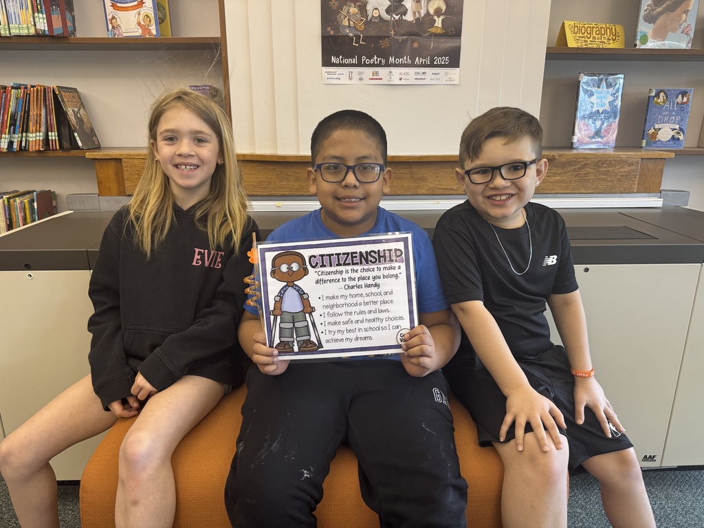three students seated together with middle child holding certificate