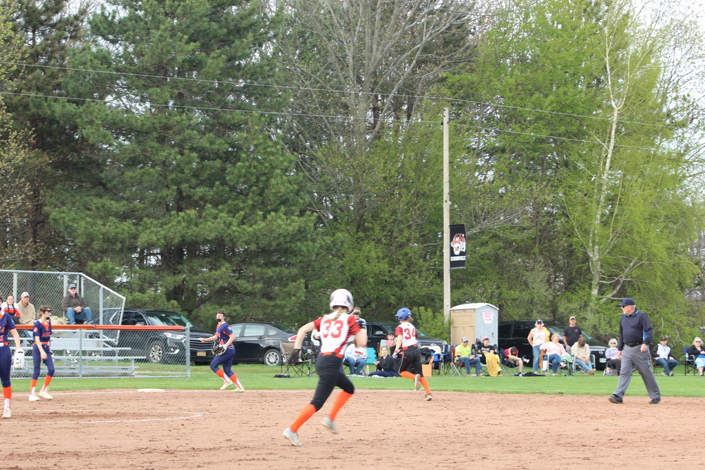 two girls running to third and second bases in softball game