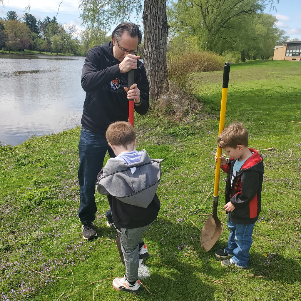 two students and teacher trying to break ground with shovel