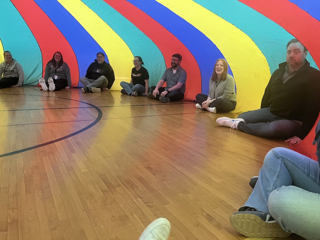 teachers sitting underneath parachute