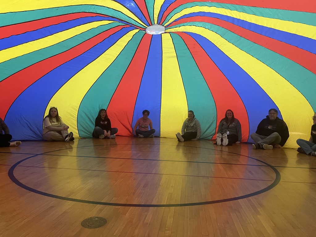 teachers sitting underneath parachute