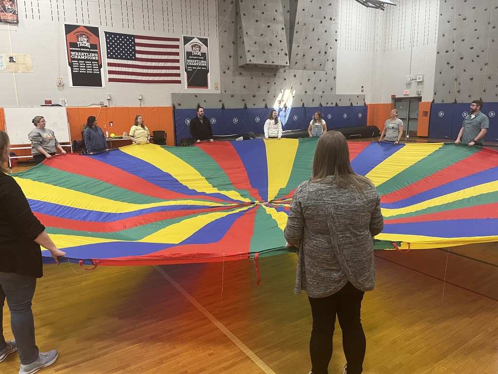 teachers stretching out parachute in the gym