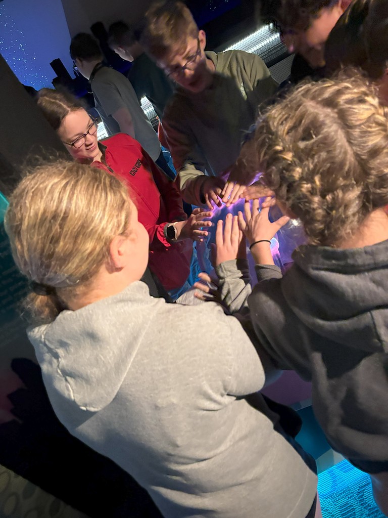 students putting hands on sphere at museum