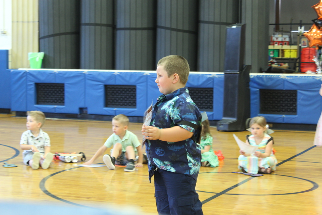boy holding certificate standing in gym