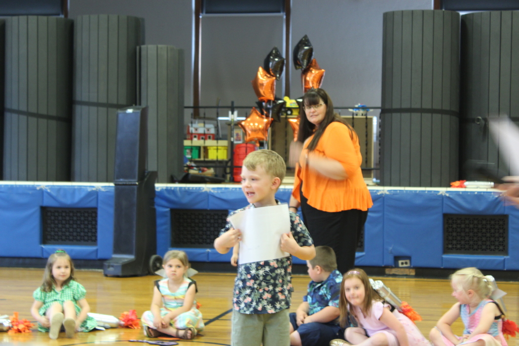 boy holding certificate standing in gym