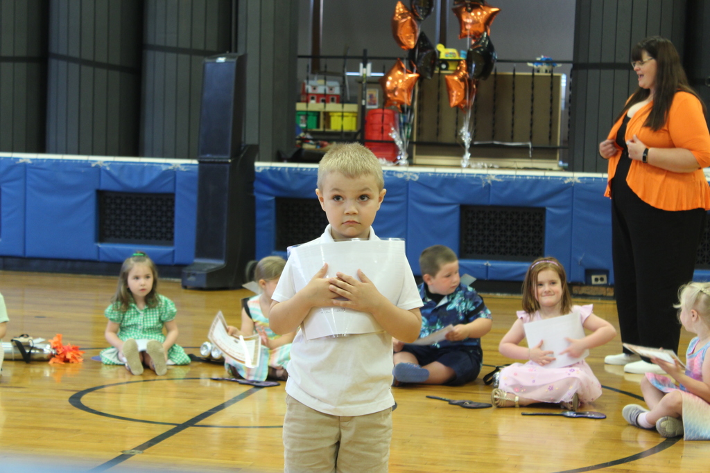 boy holding certificate standing in gym