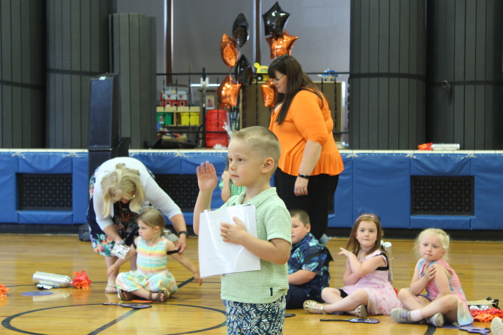 boy holding certificate standing in gym